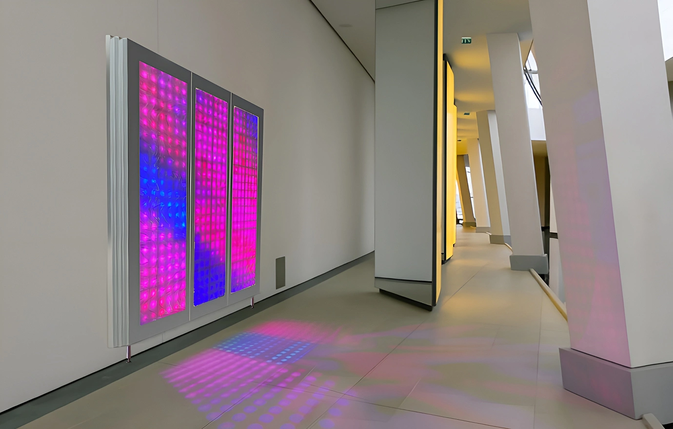 Pink and blue LED light panel installed in a modern hallway, with colorful reflections cast across the floor