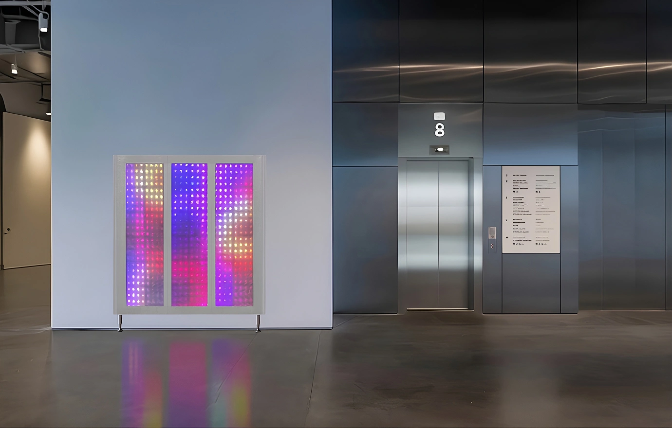 Pink and purple LED light panel displayed beside an elevator in a modern indoor lobby